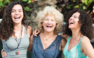 three generations of women laugh and smile for the camera