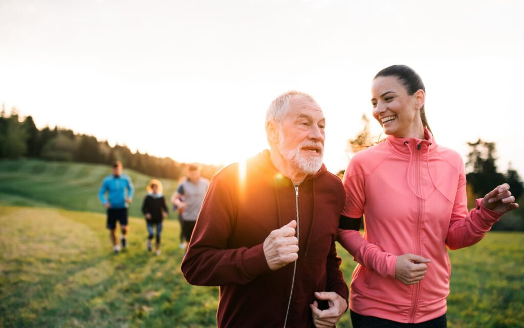 a senior exercises with his daughter at the park